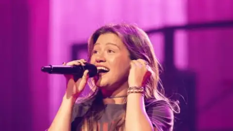 Vento levanta blusa de Kelly Clarkson em show e cantora reage: "Ah não, olha aí meus peitos"
